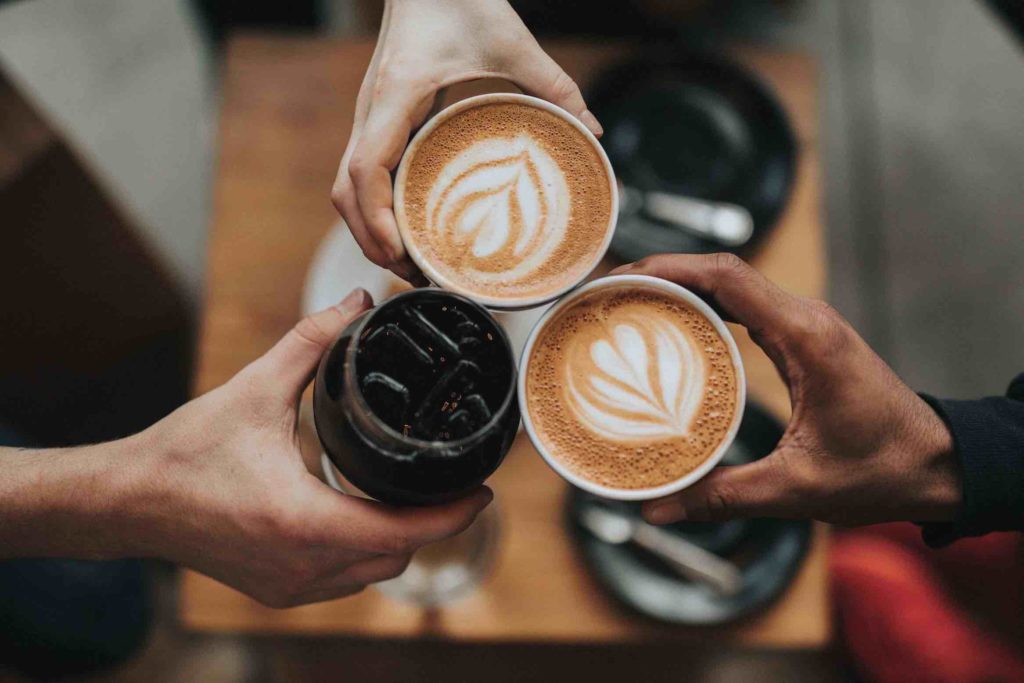 Three hands holding coffee cups